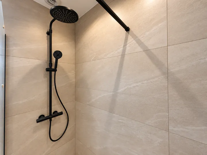 Douche en pierre beige et robinetterie noire
