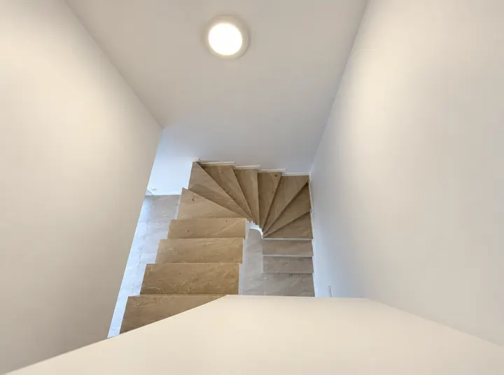 Escalier tournant en pierre beige vu d’en haut