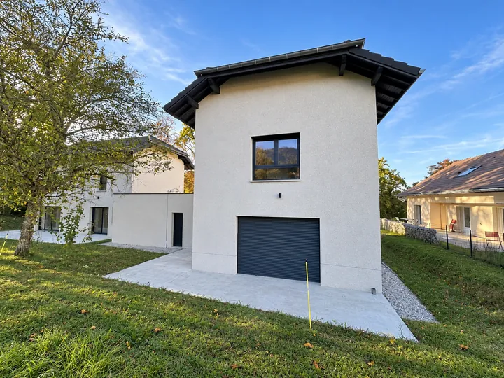 Maison contemporaine, façade beige et porte de garage anthracite côté jardin